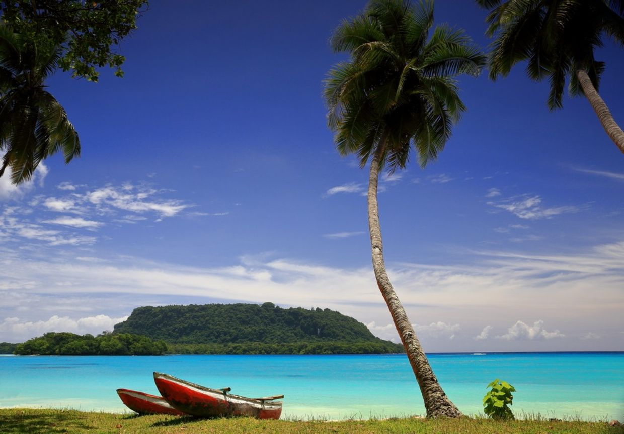 Red canoes sit on the beach in Port Olry, Vanuatu