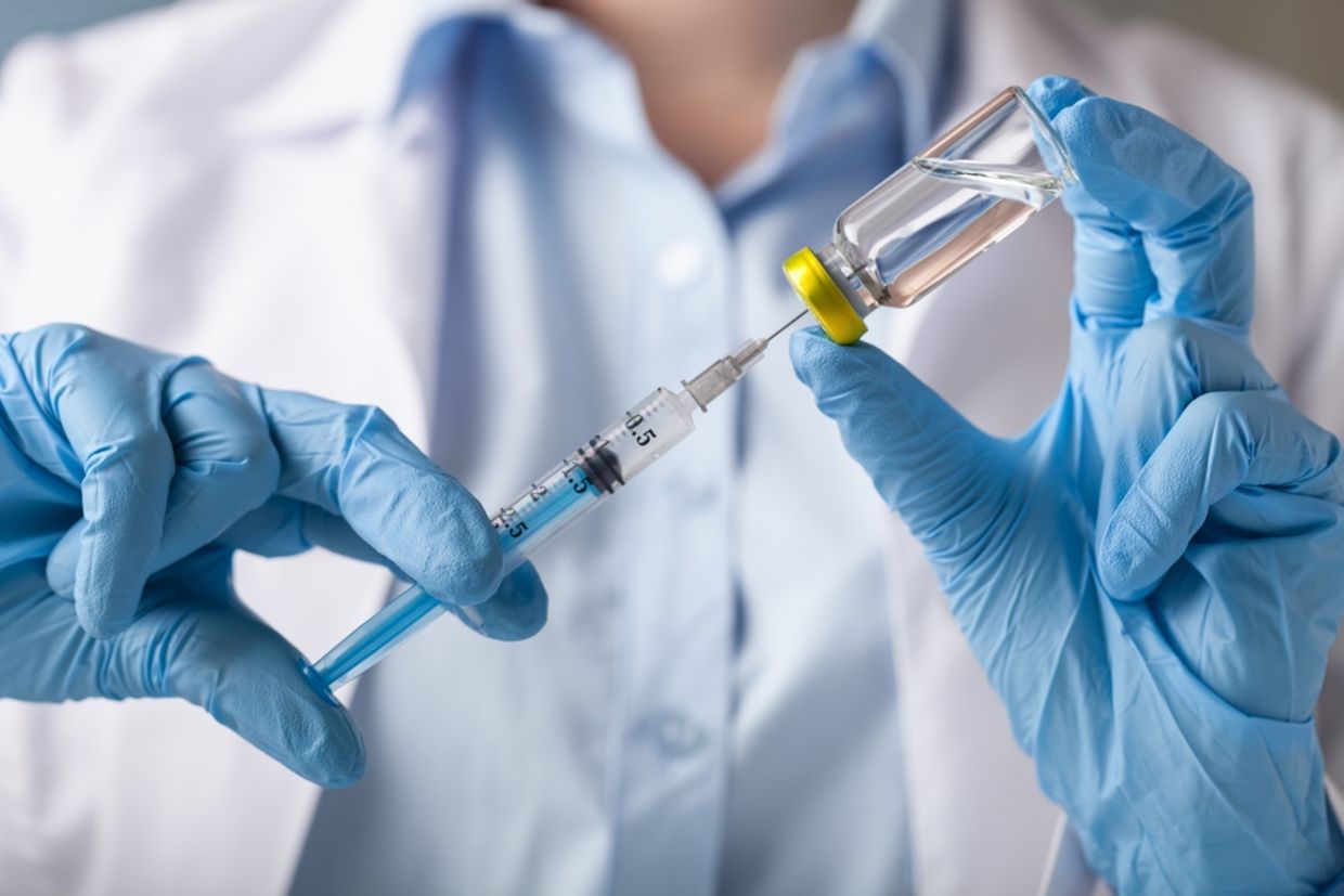 Hand holding syringe and vaccine. Hand holding syringe and vaccine.