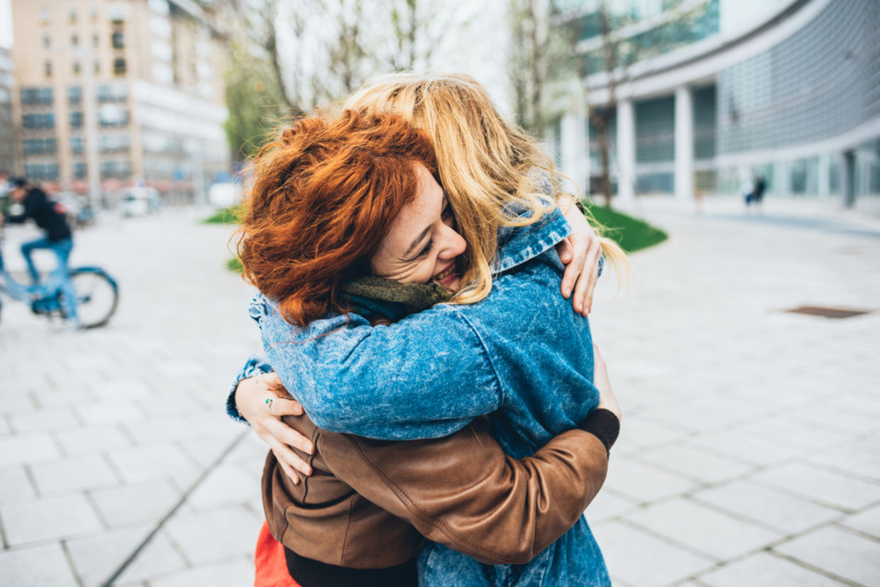 Two friends meeting in the street of the city and hugging Two friends meeting in the street of the city and hugging