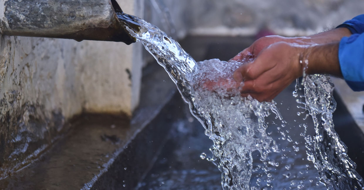 Clean water flows from a well into folded out hands Clean water flows from a well into folded out hands