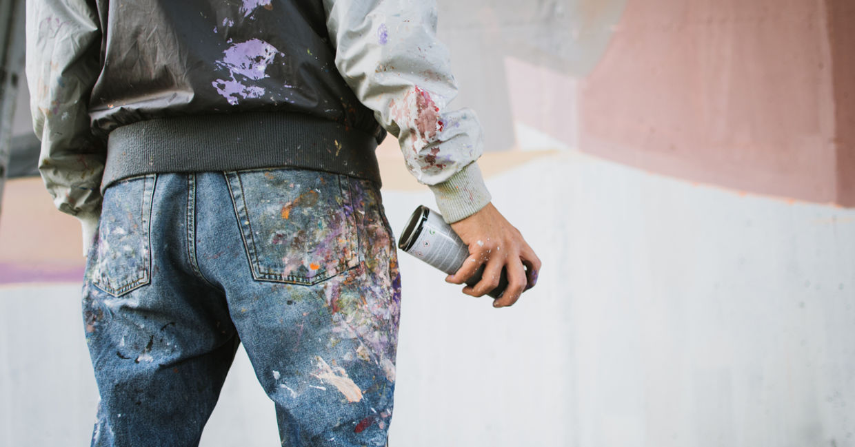 Graffiti artist with aerosol spray bottle near the wall Graffiti artist with aerosol spray bottle near the wall