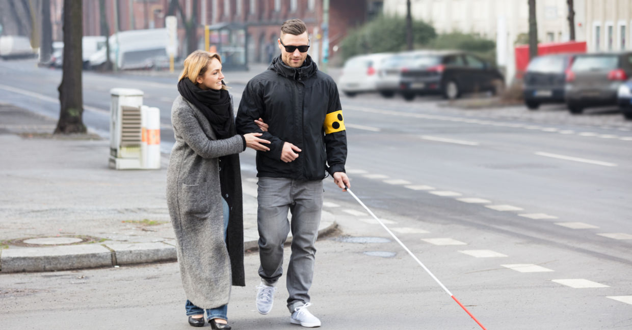 A woman helps a man cross the street A woman helps a man cross the street
