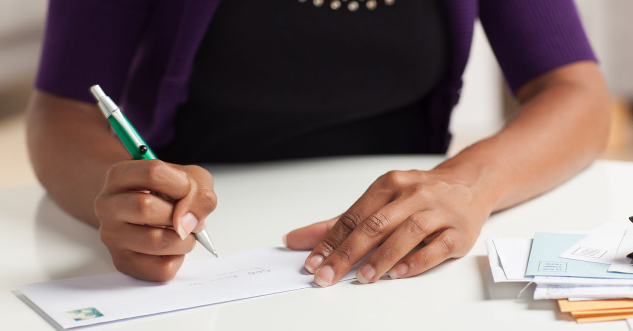 Woman writing check to charity as a good deed Woman writing check to charity as a good deed