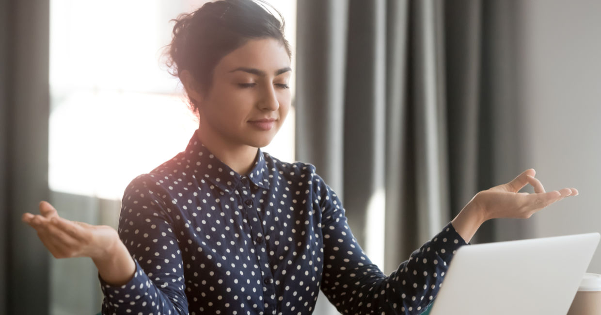 A businesswoman takes time out to meditate at her desk. A businesswoman takes time out to meditate at her desk.
