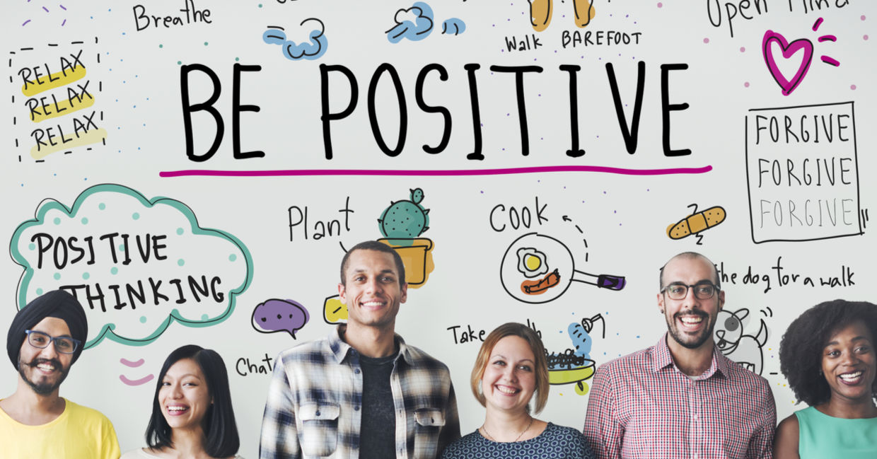 A group stands in front of a sign depicting positive thinking with images of ideas to feel good. A group stands in front of a sign depicting positive thinking with images of ideas to feel good.