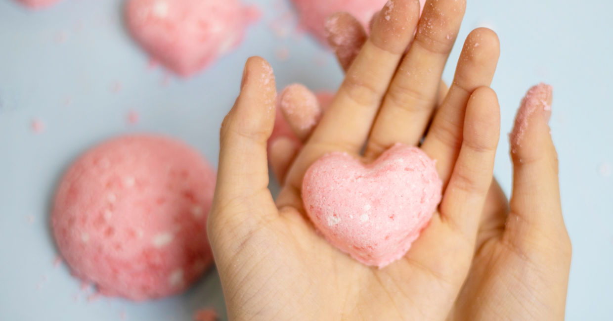 A child makes a pink bath bomb in the shape of a heart. A child makes a pink bath bomb in the shape of a heart.