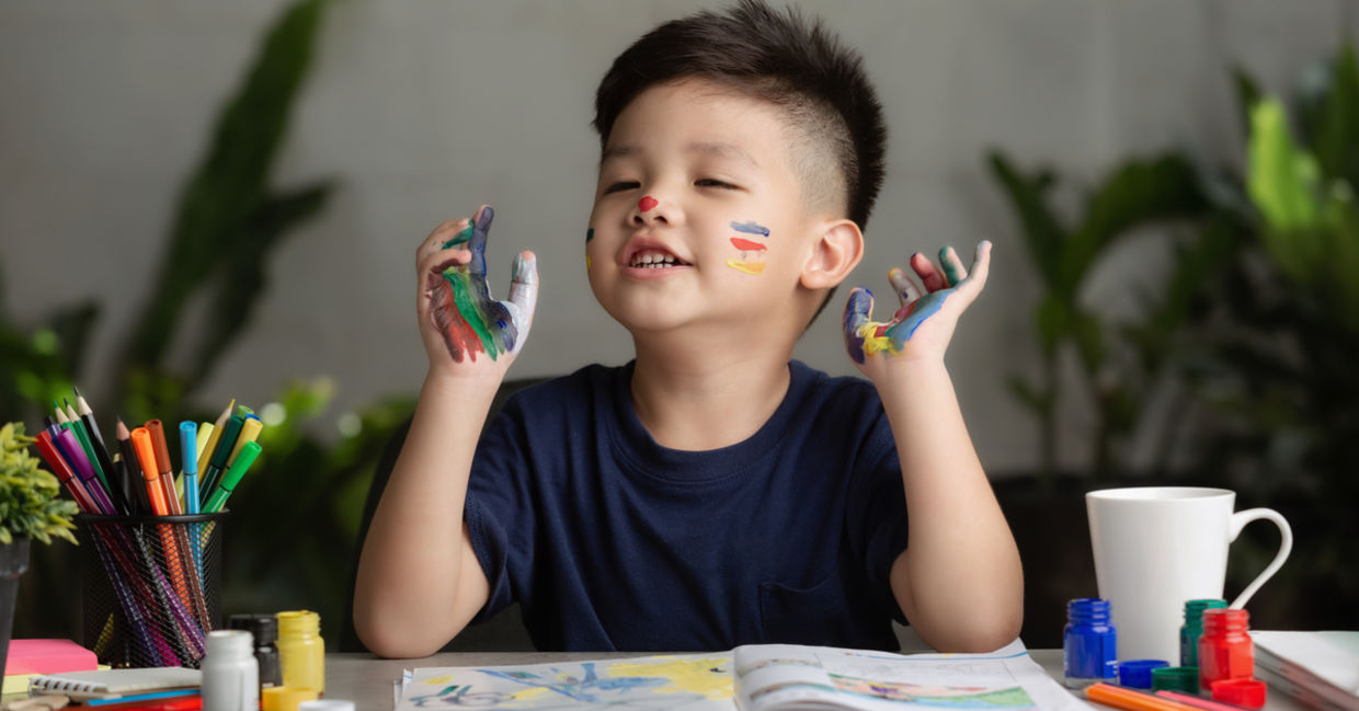 A young boy happily painting with paint all over his hands and face. A young boy happily painting with paint all over his hands and face.