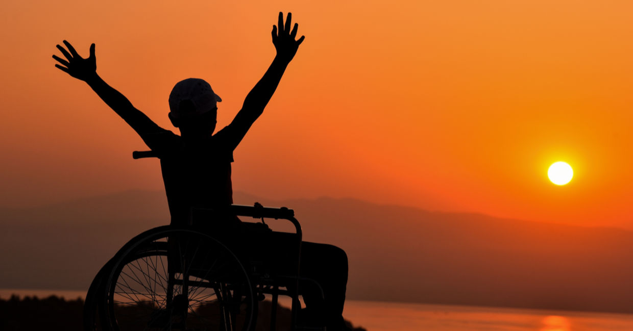 Wheelchair user enjoying a sunset by the sea Wheelchair user enjoying a sunset by the sea