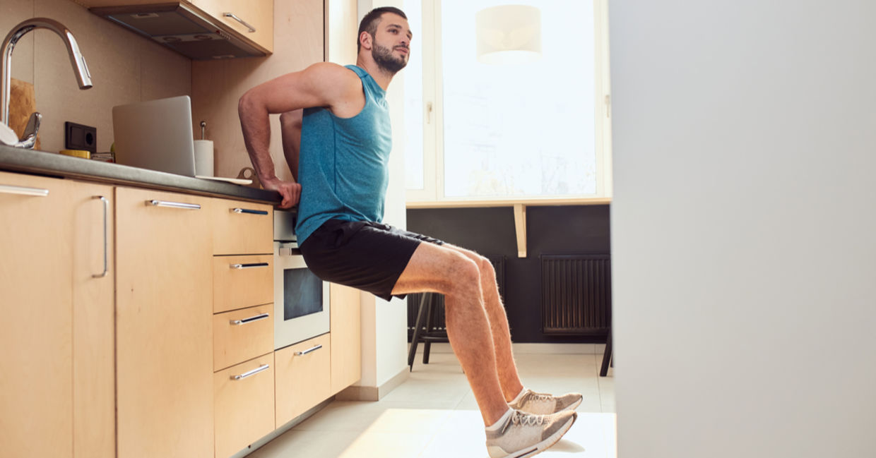 A young man exercising using the kitchen counter. A young man exercising using the kitchen counter.