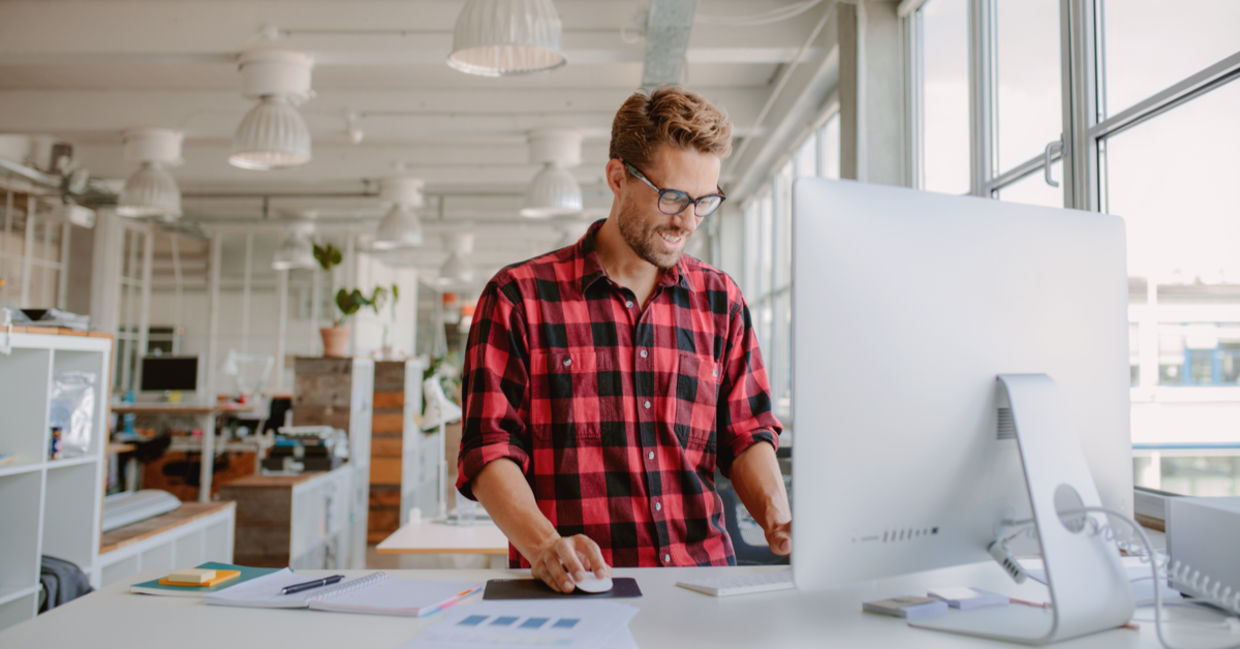 Happy young man working at a standing desk Happy young man working at a standing desk