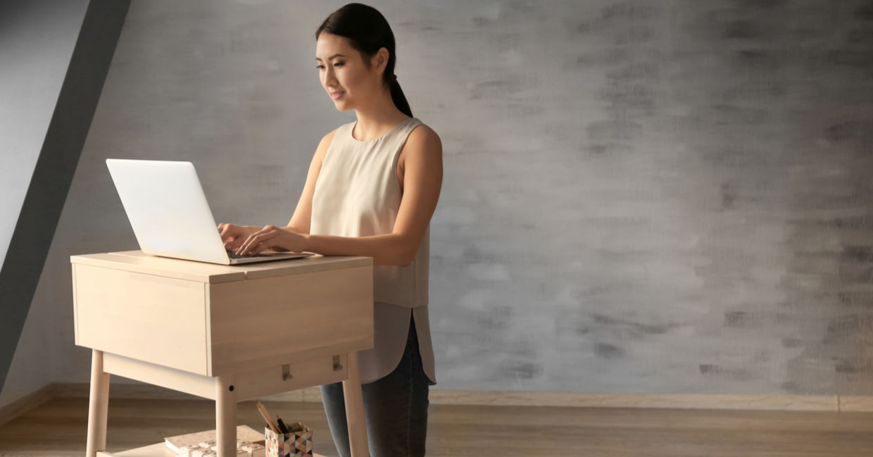 Woman typing on laptop at stand-up workplace Woman typing on laptop at stand-up workplace