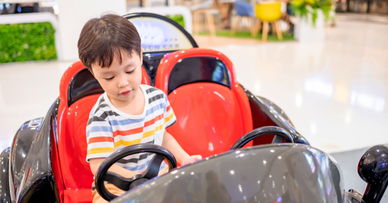 A young boy is riding in a coin-operated car. A young boy is riding in a coin-operated car.