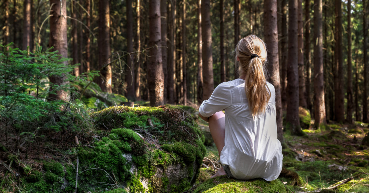Woman sitting in green forest enjoys the silence and beauty of nature Woman sitting in green forest enjoys the silence and beauty of nature