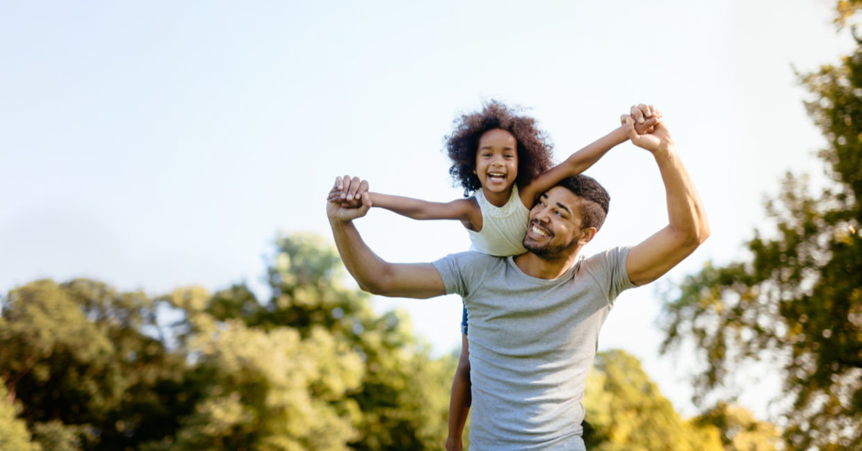 Father carrying daughter on his back outdoors Father carrying daughter on his back outdoors