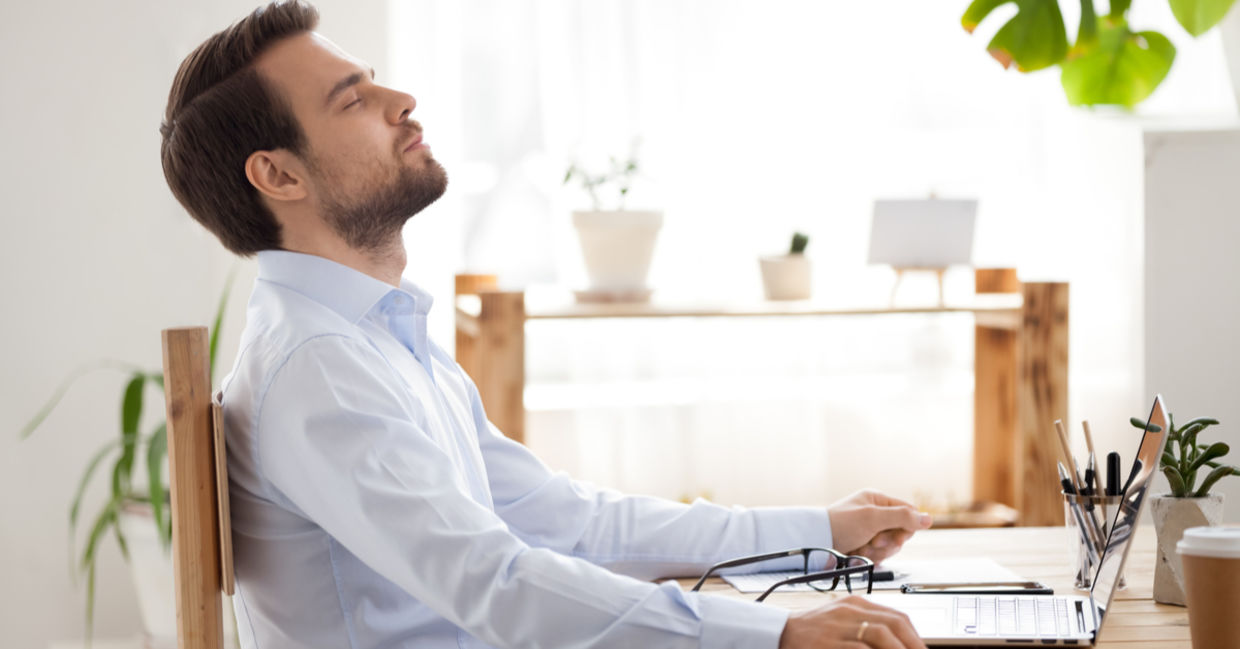 A man takes a break from work and practices mindfulness at his work. A man takes a break from work and practices mindfulness at his work.