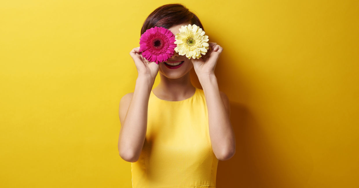 Happy woman covering her eyes with flowers Happy woman covering her eyes with flowers
