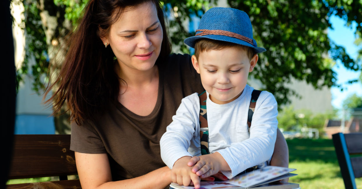 Happy mother listening to her son as he reads his book out loud. Happy mother listening to her son as he reads his book out loud.