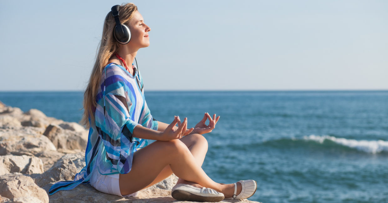 A woman meditates to the relaxing soundwaves of binaural beats. A woman meditates to the relaxing soundwaves of binaural beats.