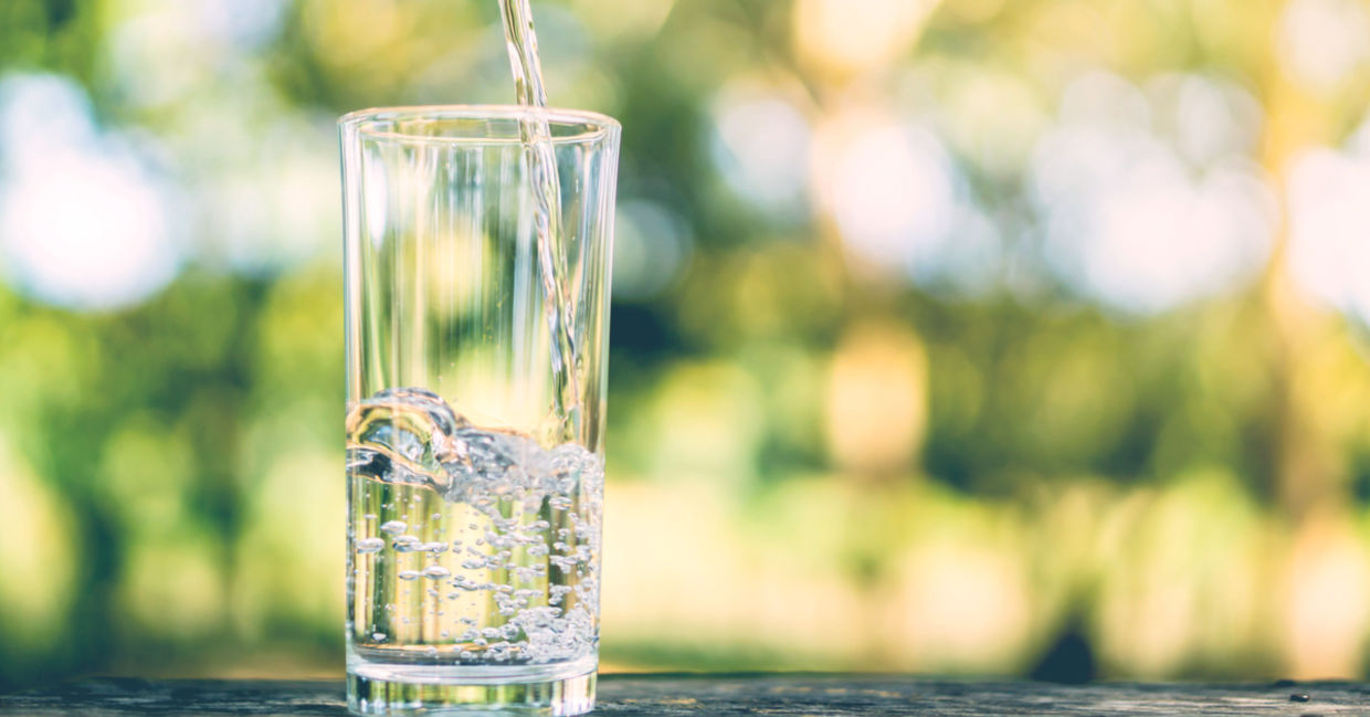 Pouring fresh water into a drinking glass on a sunlit morning. Pouring fresh water into a drinking glass on a sunlit morning.