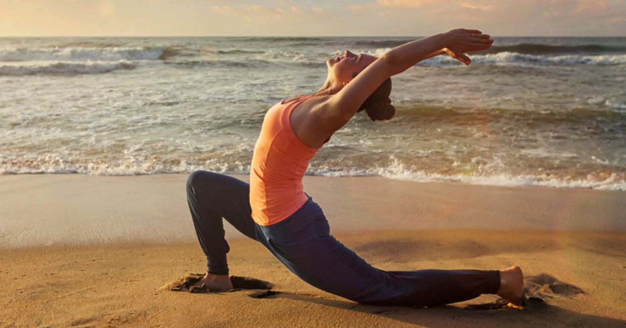 A woman practices the crescent lunge yoga pose on the beach. A woman practices the crescent lunge yoga pose on the beach.