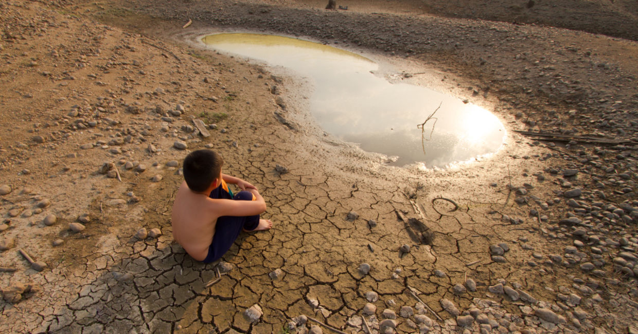 A child sitting near by a water source. A child sitting near by a water source.
