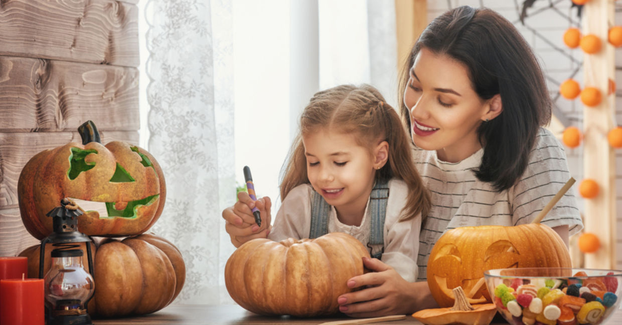 A mother carves a pumpkin for Halloween with her young daughter. A mother carves a pumpkin for Halloween with her young daughter.