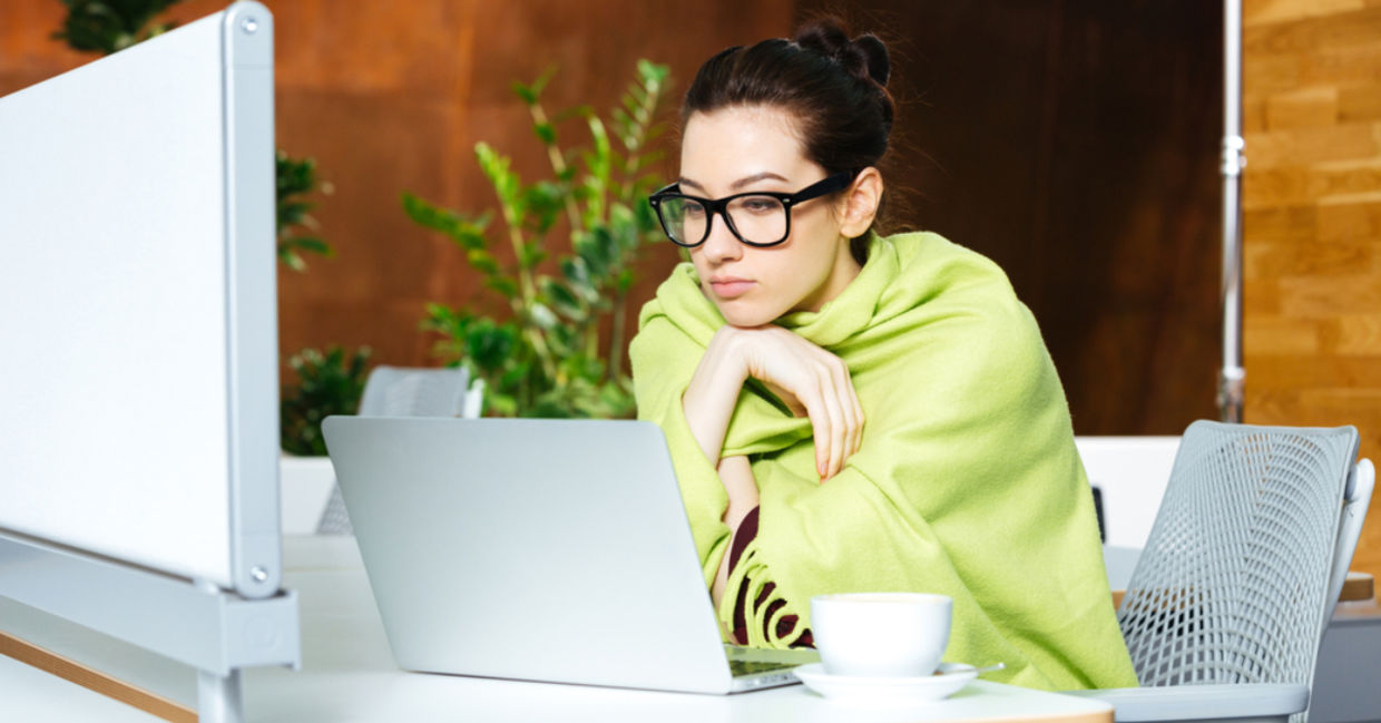 Woman wrapped in a shawl due to feeling cold in her workspace. Woman wrapped in a shawl due to feeling cold in her workspace.