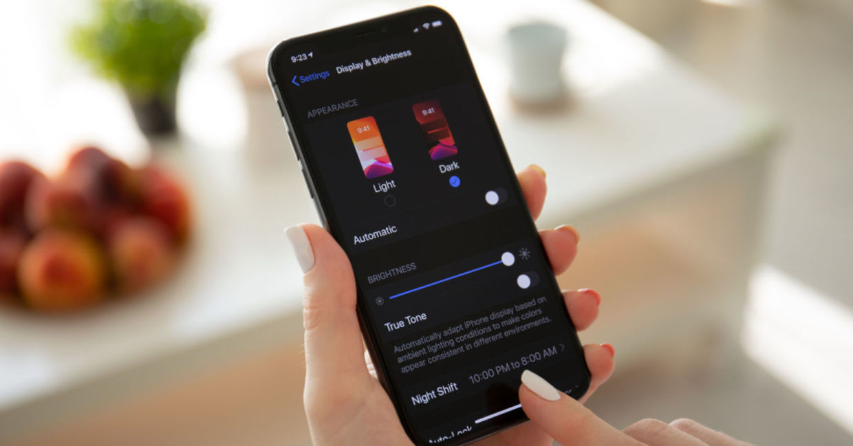 A woman looks at her smartphone in dark mode. A woman looks at her smartphone in dark mode.