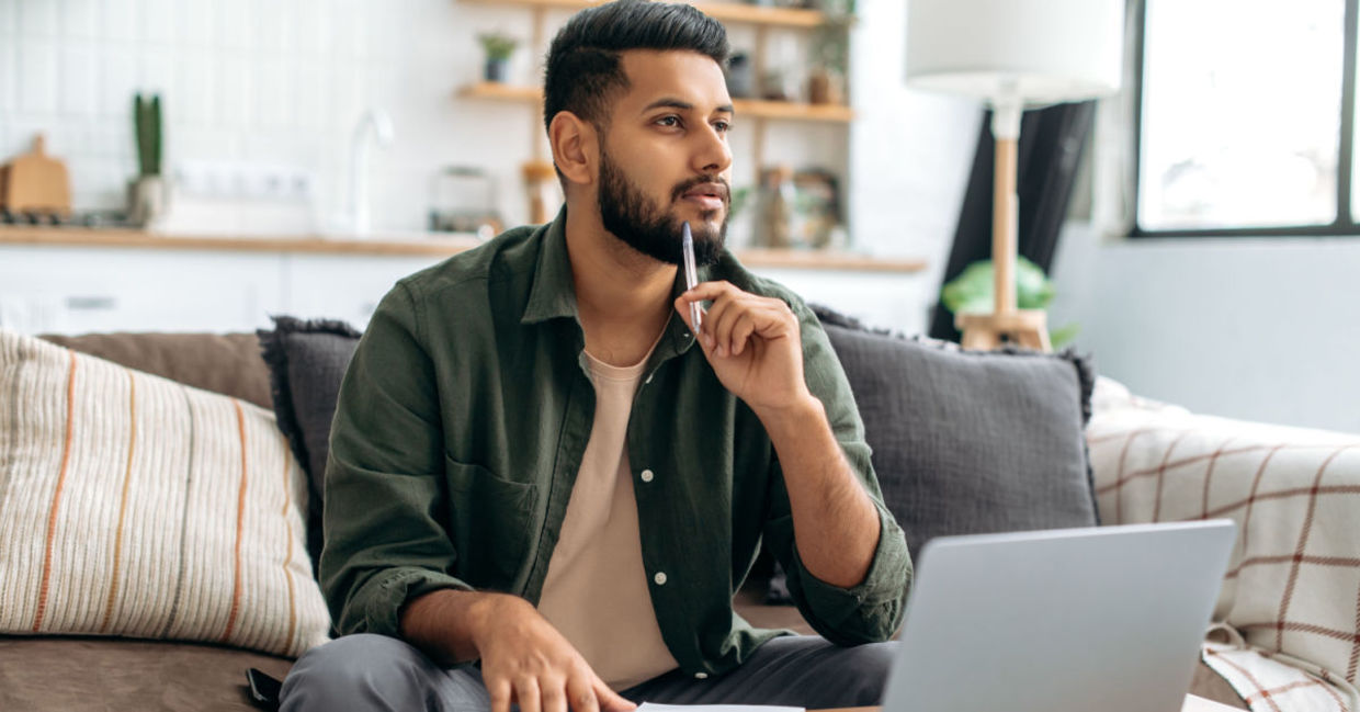 A man takes a break by looking away from his laptop. A man takes a break by looking away from his laptop.