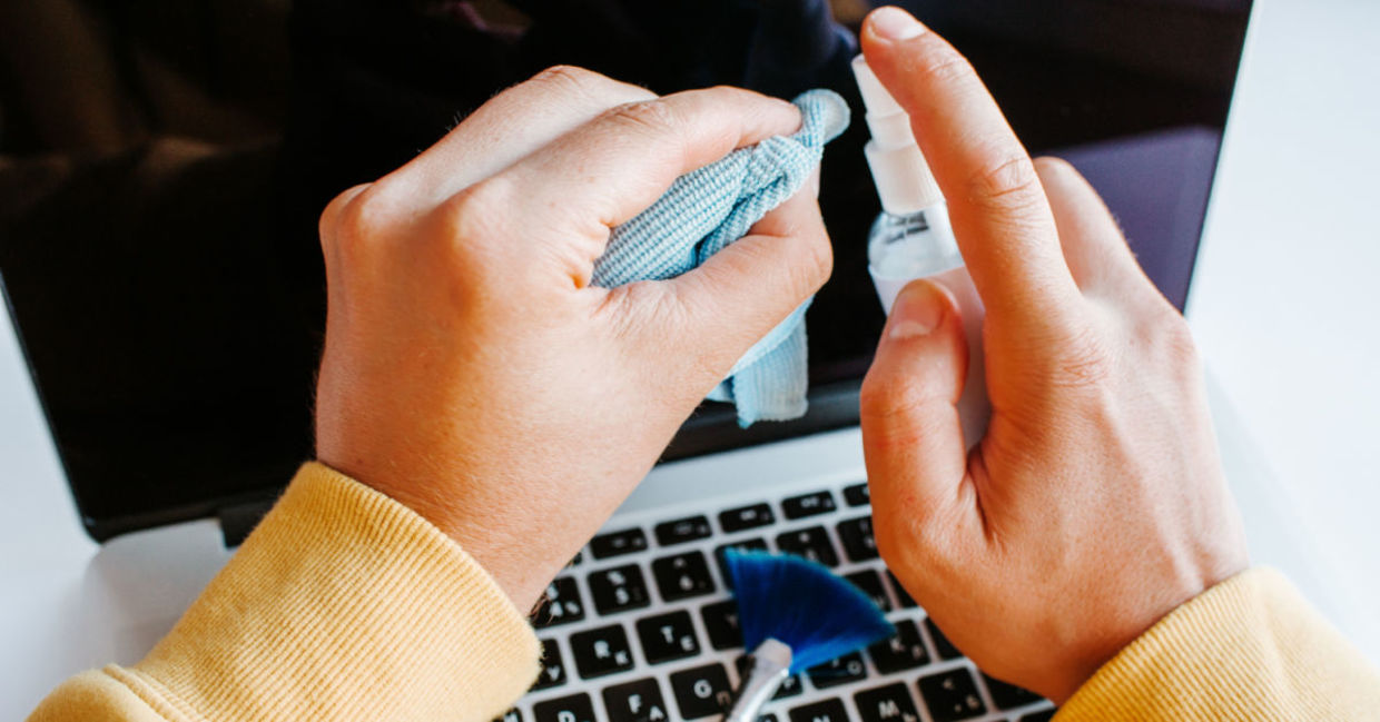 A man cleans his screen with spray and a cloth. A man cleans his screen with spray and a cloth.