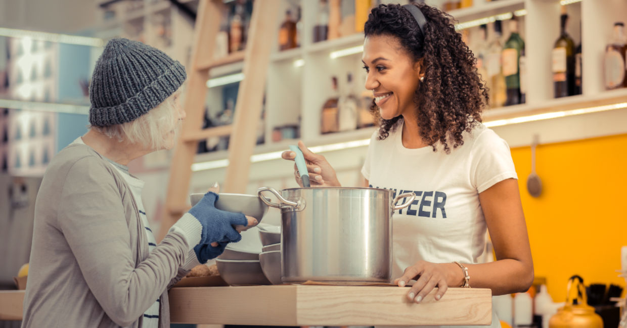 A volunteer giving soup to the homeless. A volunteer giving soup to the homeless.