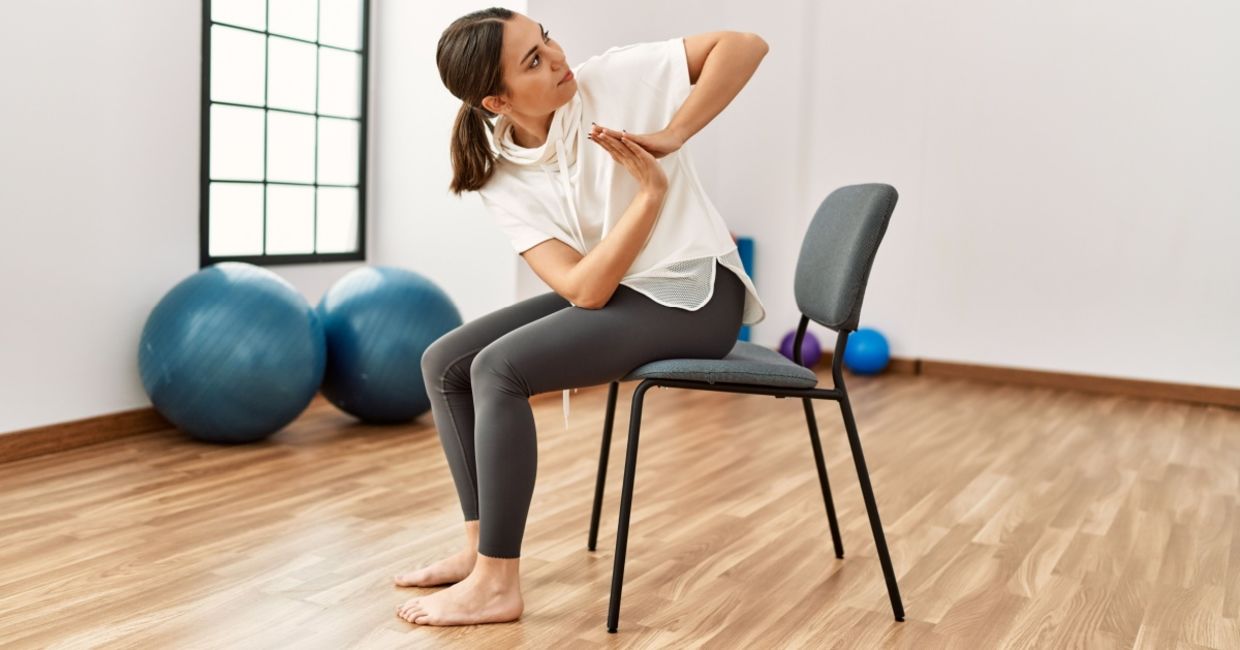 Woman performing chair yoga at a fitness center. Woman performing chair yoga at a fitness center.