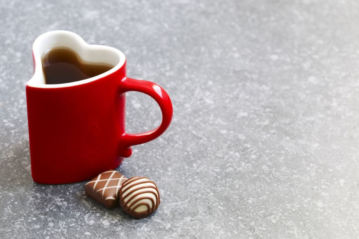 A mug on a table with chocolates next to it. A mug on a table with chocolates next to it.